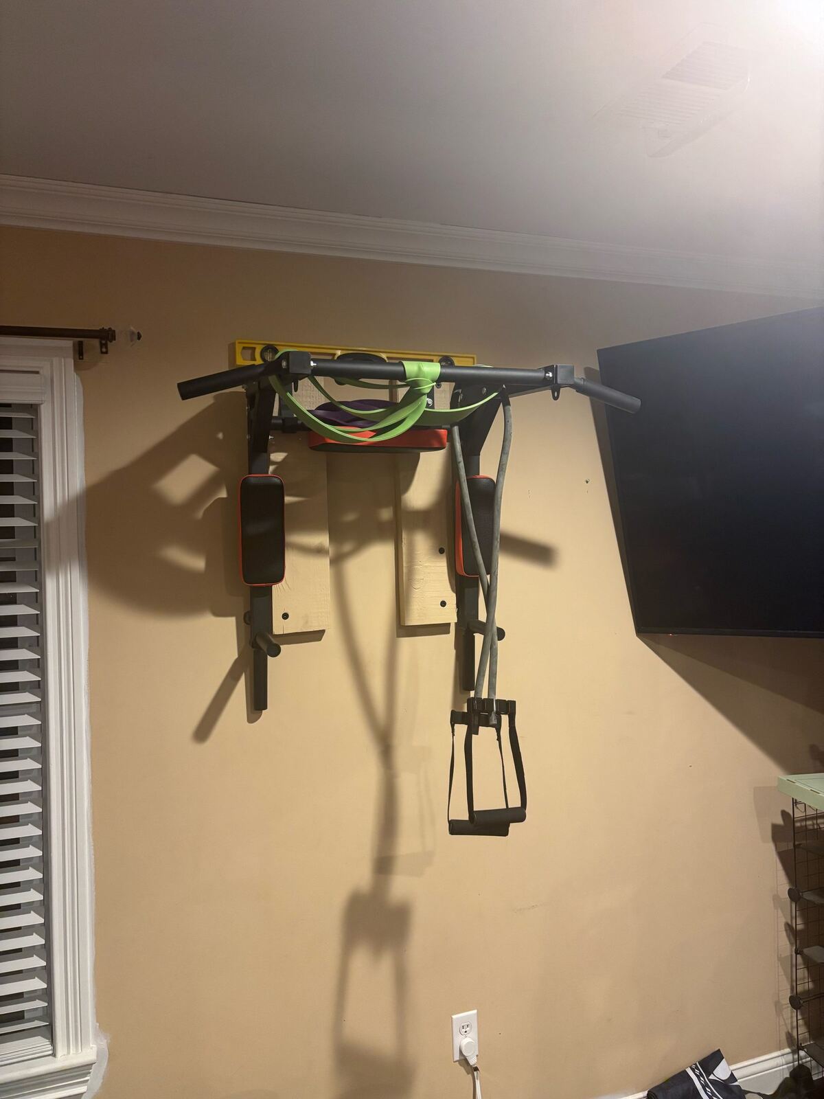 Wall-mounted pull-up and dip tower bolted to wooden stud supports — not a doorway bar — site owner’s owned gear